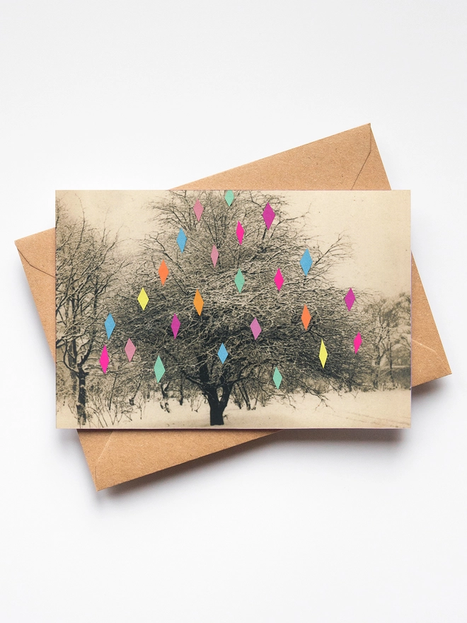 A pretty Christmas card featuring a decorated tree in a snowy landscape.