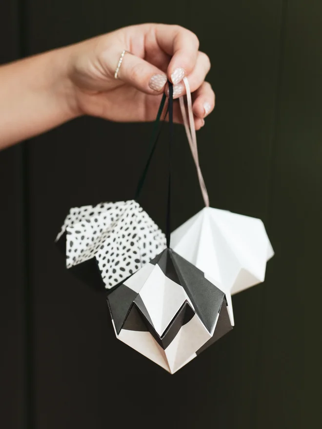 Woman's hand holding origami diamond ornaments from ribbon