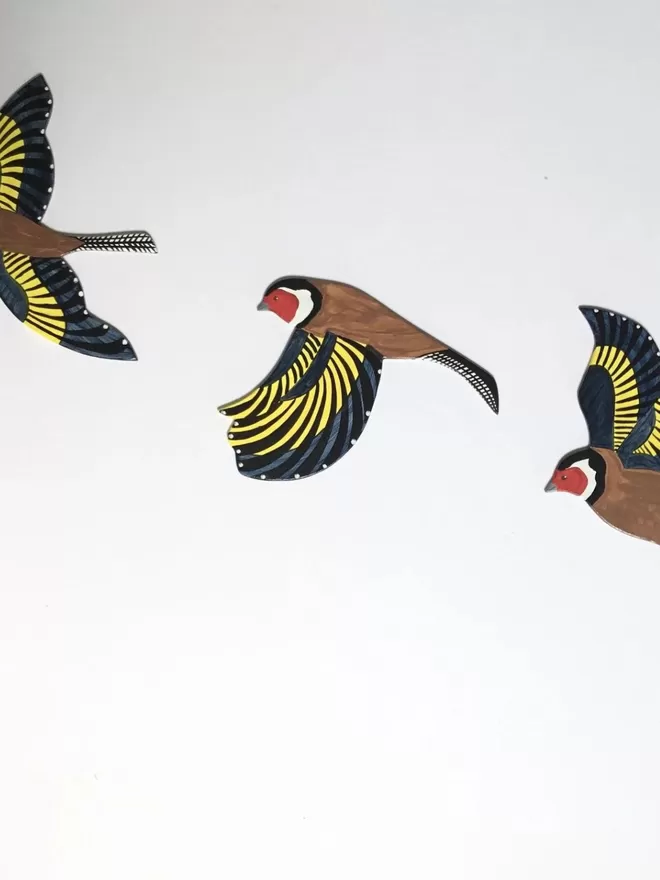 3 wooden goldfinches hanging on a white wall