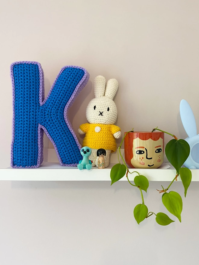 Crocheted Letter K in Blue and Lilac, on a child's shelf