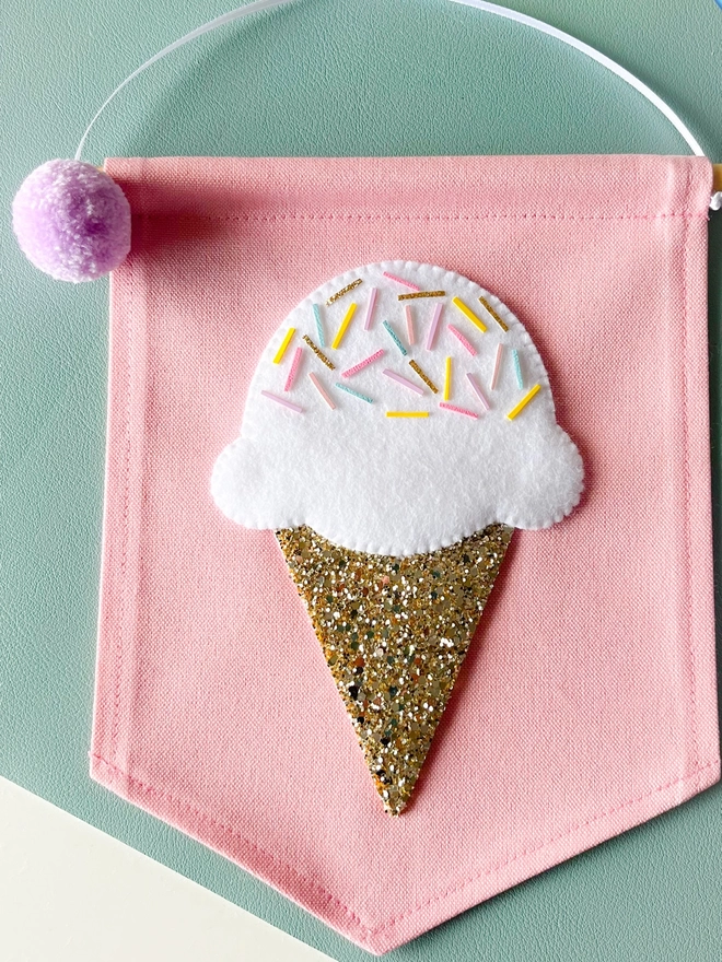 White ice cream banner on a pink background with a gold glitter cone