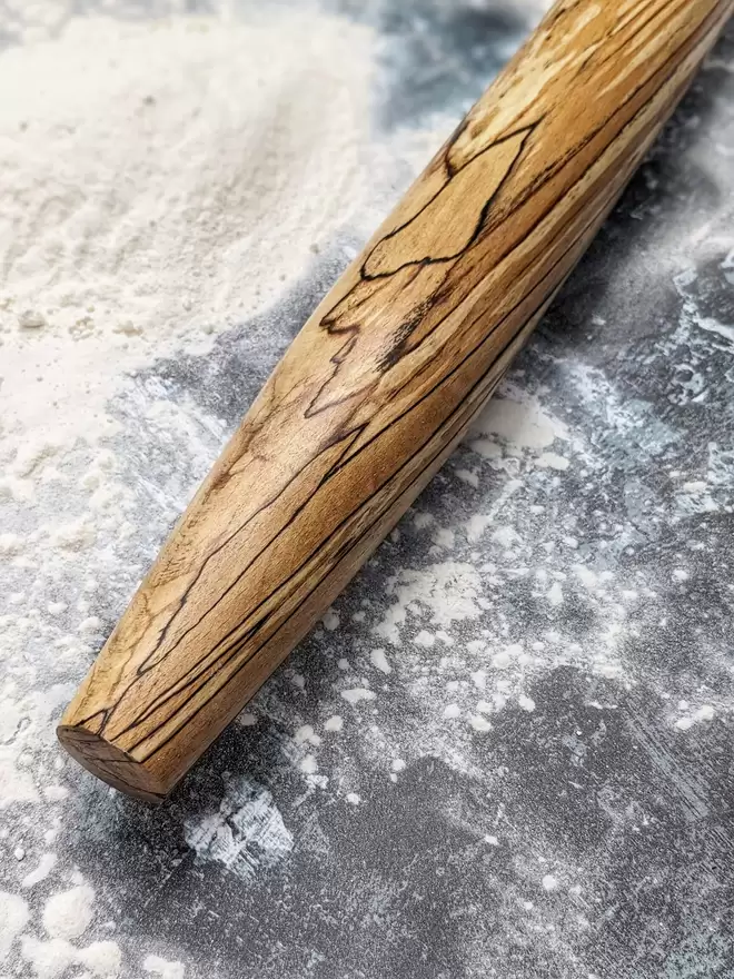 A close up of a stunning hand made rolling pin in Spalted Beech by Something From The Turnery. Displaying the all-natural flame like detailing on the left hand side of the rolling pin.