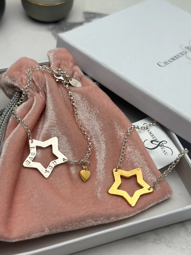 personalised sterling silver open star charm on a silver belcher chain bracelet with additional tiny heart charm in gold. also a gold version of the bracelet with gift box and pouch