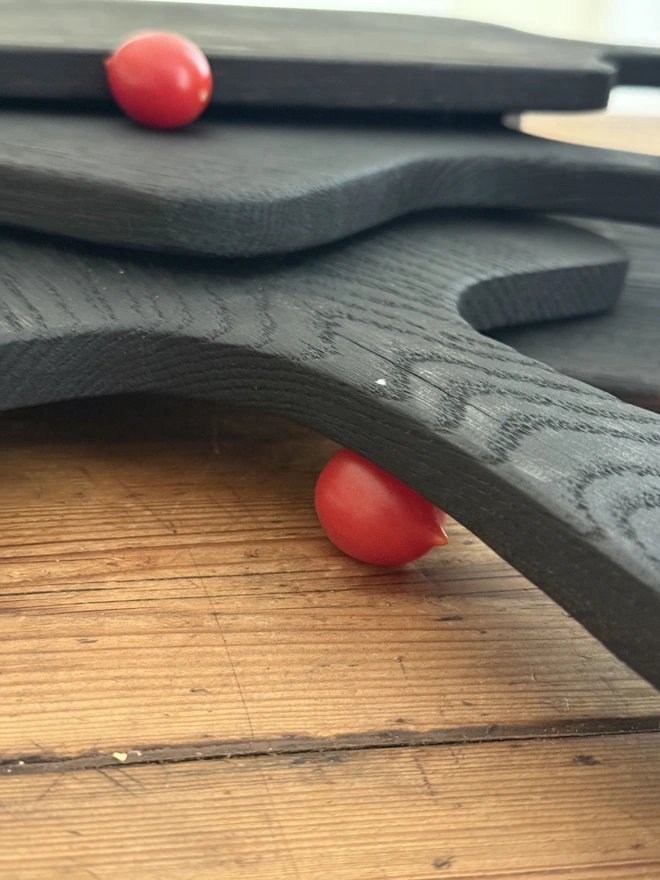 Side angle of pile of serving boards and baby tomatoes 