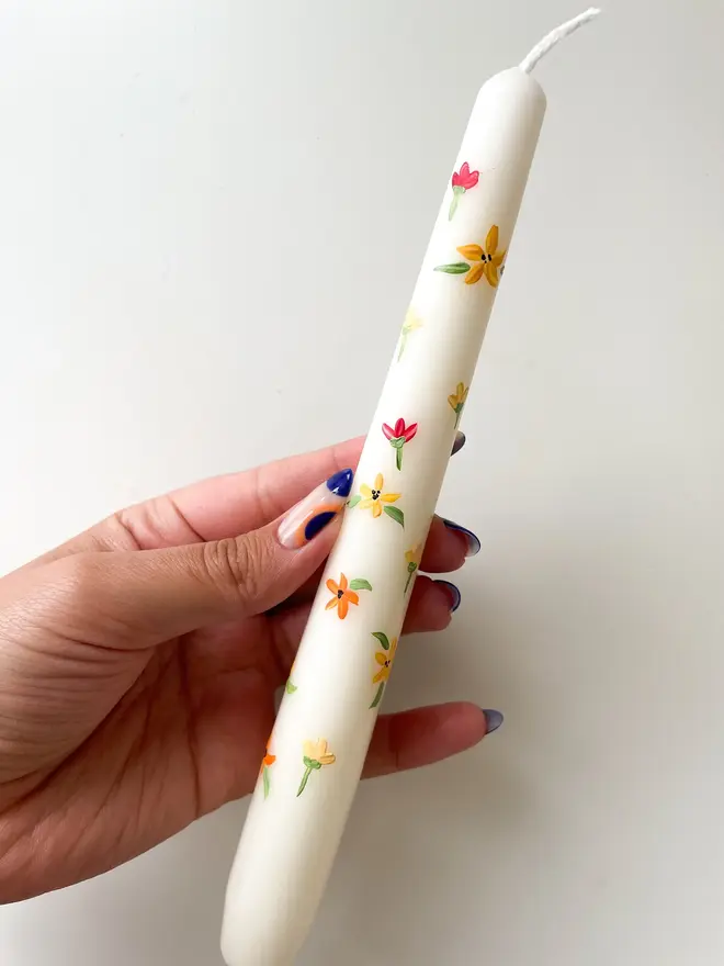 Blooming For You & Spring Bound Hand Painted Candle, a taper candle against a white surface. The floral design can be seen wrapping around them. 