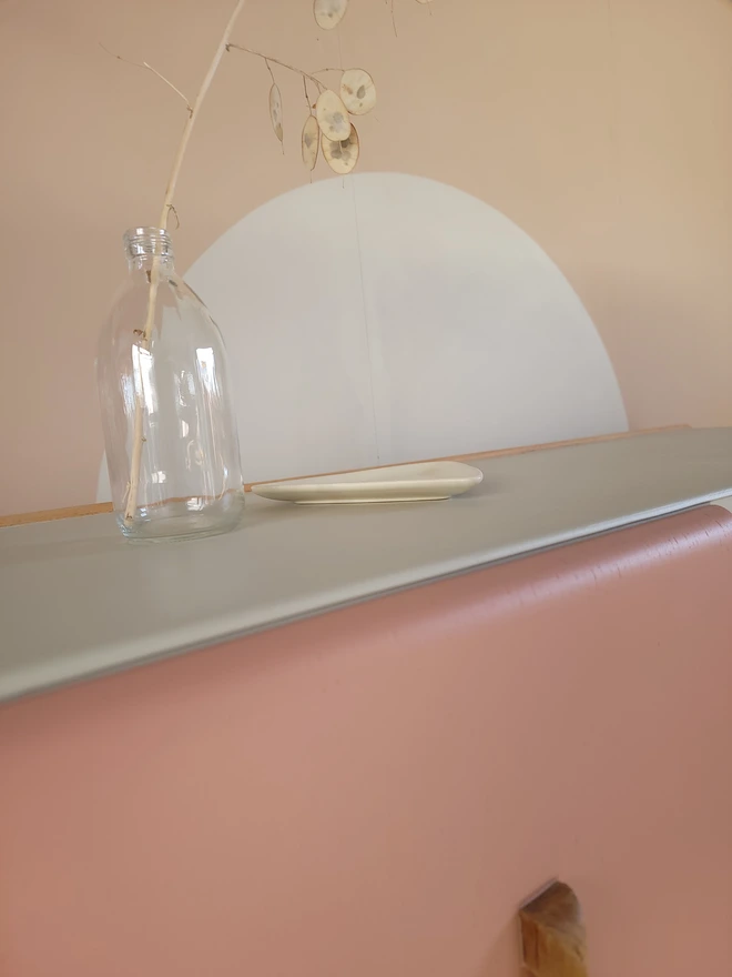 Close up of the top of a greige sideboard with pink painted door
