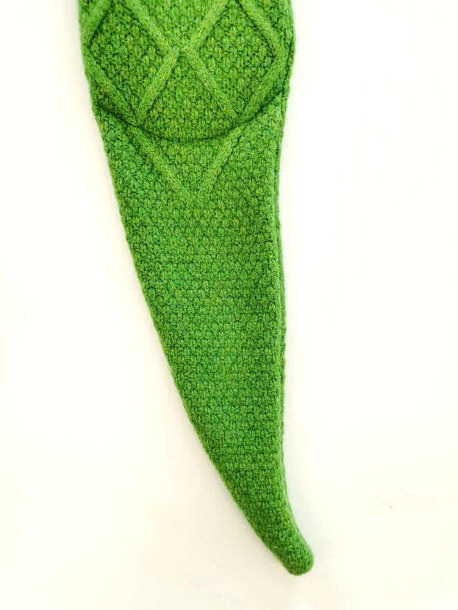 A close up detail of the crocodile hot water bottle tail and diamond moss stitch back pattern.