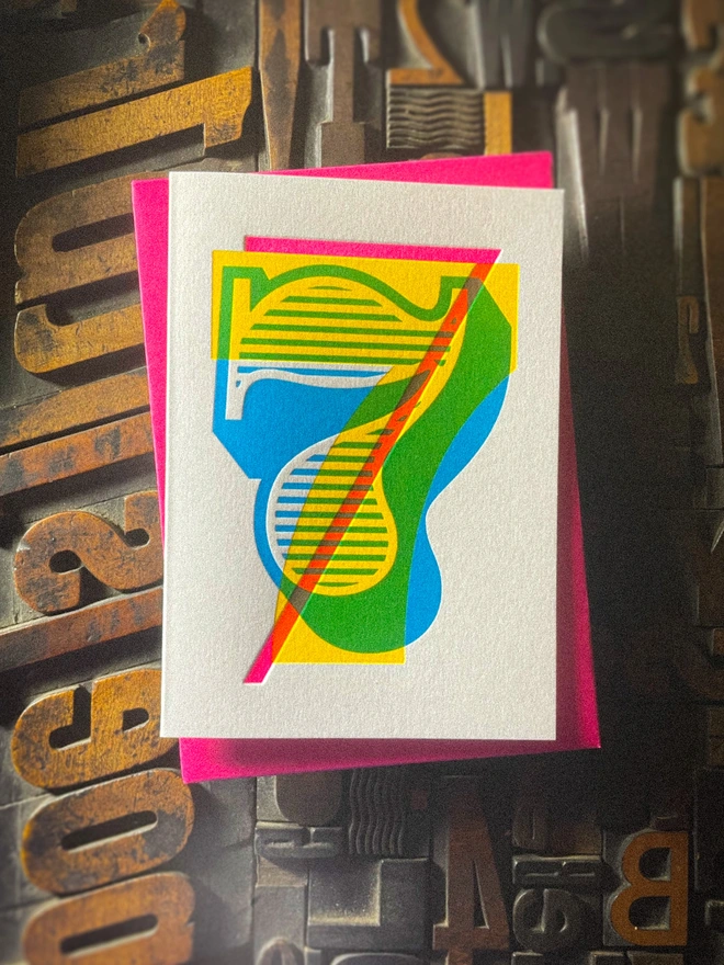 Handmade letterpress 7th birthday card featuring bold overlapping numerals printed in vibrant fluorescent cyan, magenta and yellow inks. Each card is individually hand printed using traditional letterpress techniques on luxury paper stock, creating a beautifully tactile finish with a deep impression and rich layered colours inspired by the CMYK printing process. Printed on a traditional letterpress from 1915. A wonderful artisan printed birthday card.