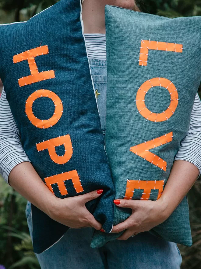 Love Welcomes LOVE and HOPE cushions seen together.