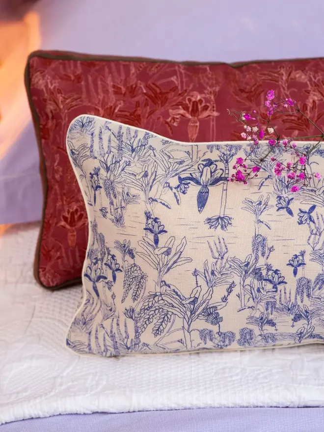 white and red tropicalia cushions on a bed