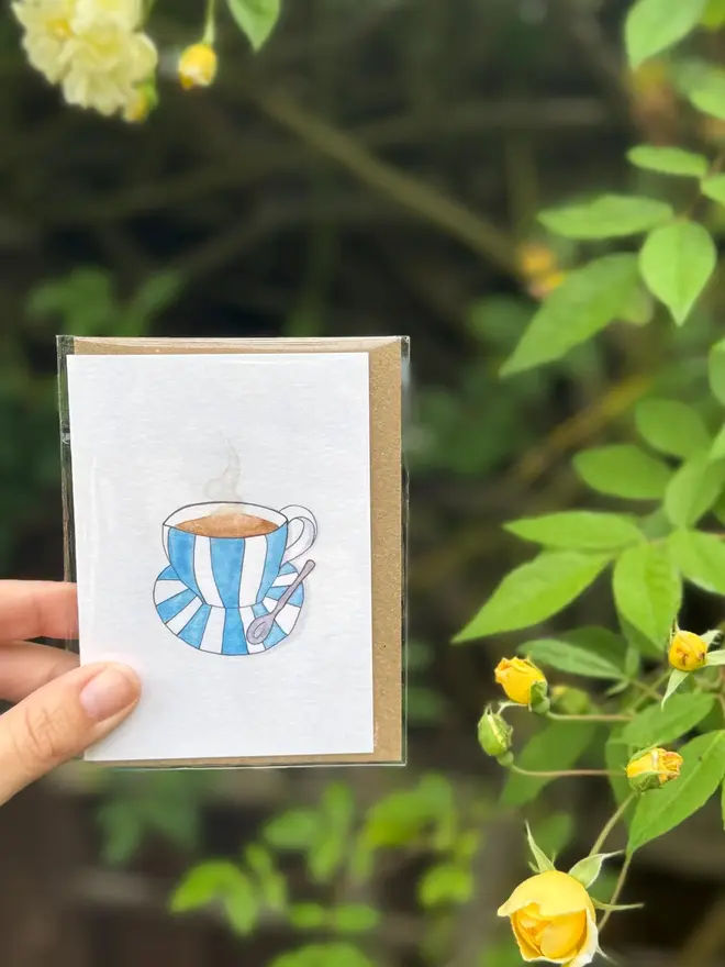 cup and saucer illustrated mini cards (pack of 3). card photographed against rosebush backdrop.