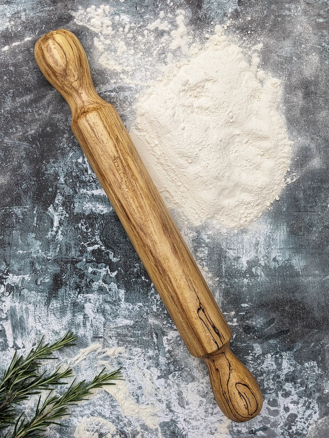 A stunning hand made rolling pin in Spalted Beech by Something From The Turnery. The rolling pin sits on an art house kitchen top amongst flour and fresh rosemary, prepped to bake some delicious bread!