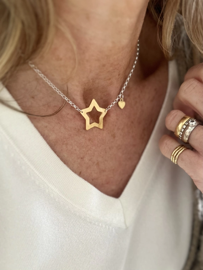 model wears sterling silver chain with gold open star charm and gold mini heart charm