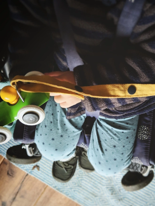 Handmade toy strap attached to a wooden toy and pushchair.