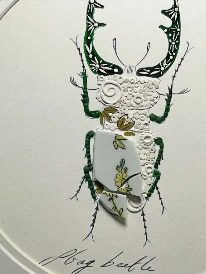 Hand-drawn, painted, mosaic clay, green Willow Tree pottery insect on white double mounted card, in a black circular frame.