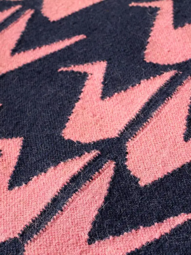 Crane Flatweave Rug, a colourful rug sitting on a plain surface. 