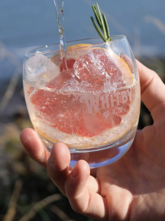 Original Edition Gin, a person holding a glass of gin outdoors. 