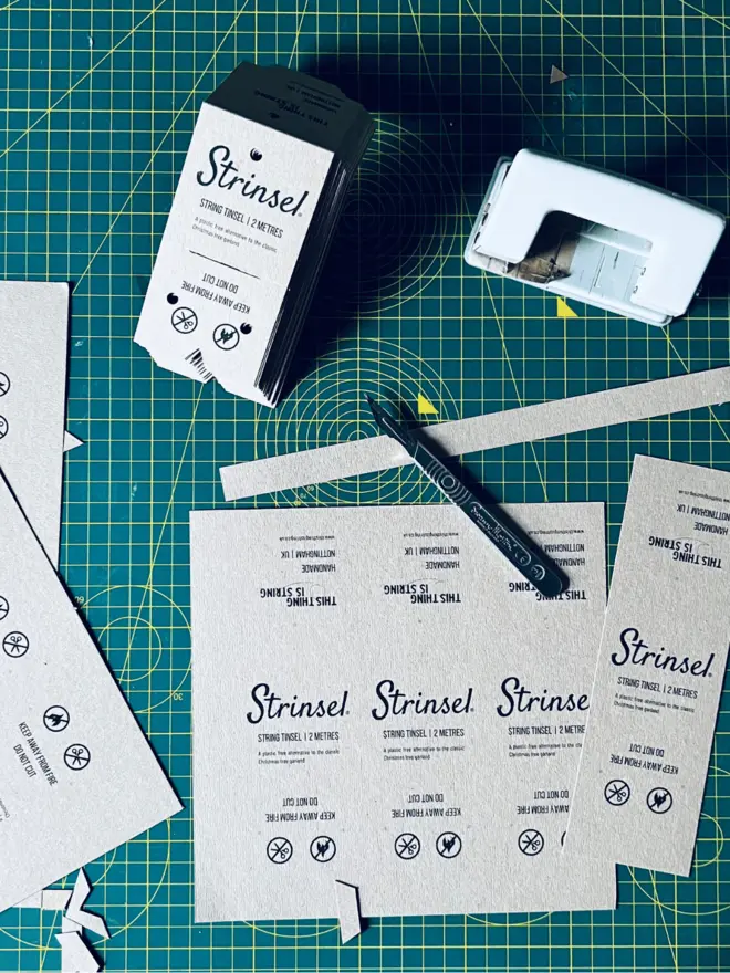 Strinsel labels being made on a green cutting mat surrounded by tools