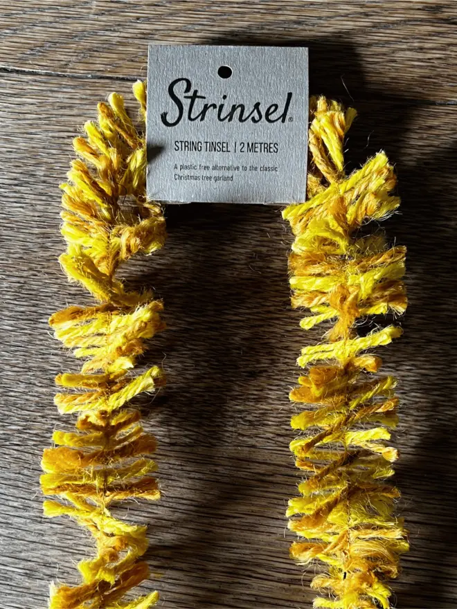 Classic Gold Strinsel with label AKA Jute string tinsel on an oak table