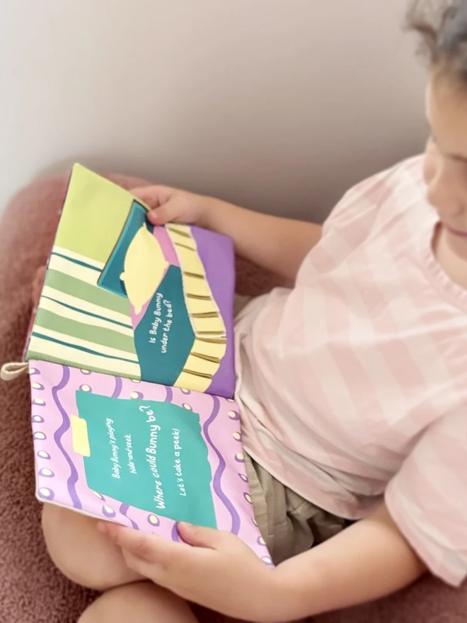 Girl holding an open Where's Baby Bunny? Lift-the-flap Cotton Soft Book