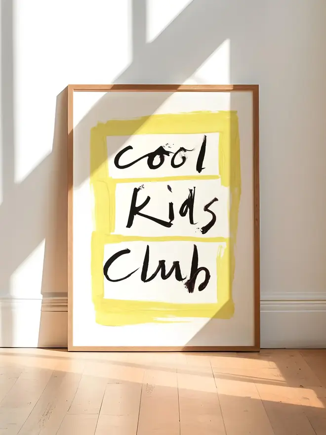 'cool kids club' art print. a print with a white and yellow background with a slogan in black lettering in a wooden frame.