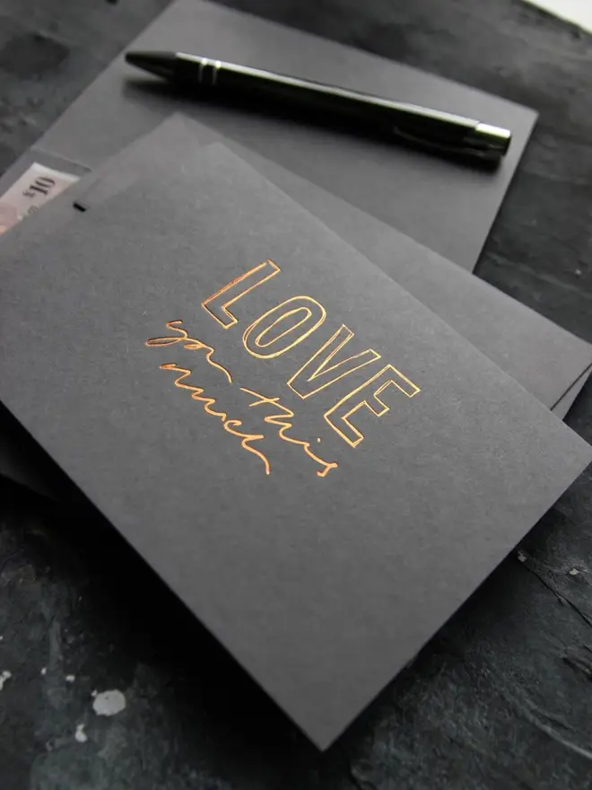 Hand foiled cash card or money wallet in a smoke grey colour in shiny bronze foil text which says ‘love you this much’.