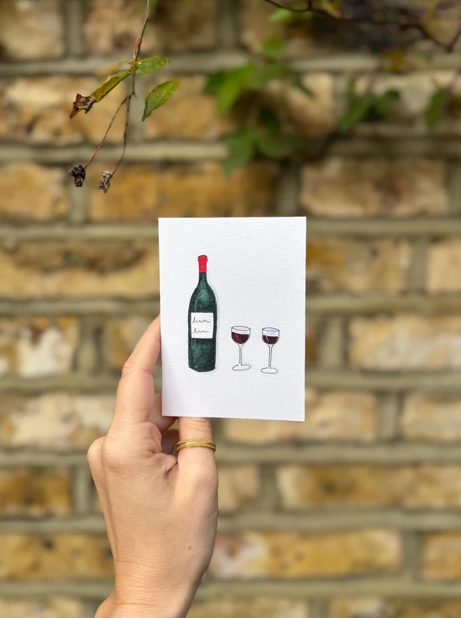 red wine illustrated mini card. card photographed against brick wall background.