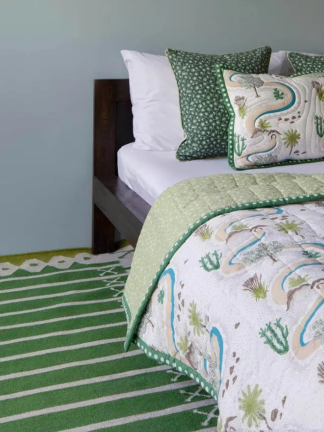 Darjeeling Flatweave Rug, a colourful rug in a bedroom. It is accompanied by other bedding accessories. 