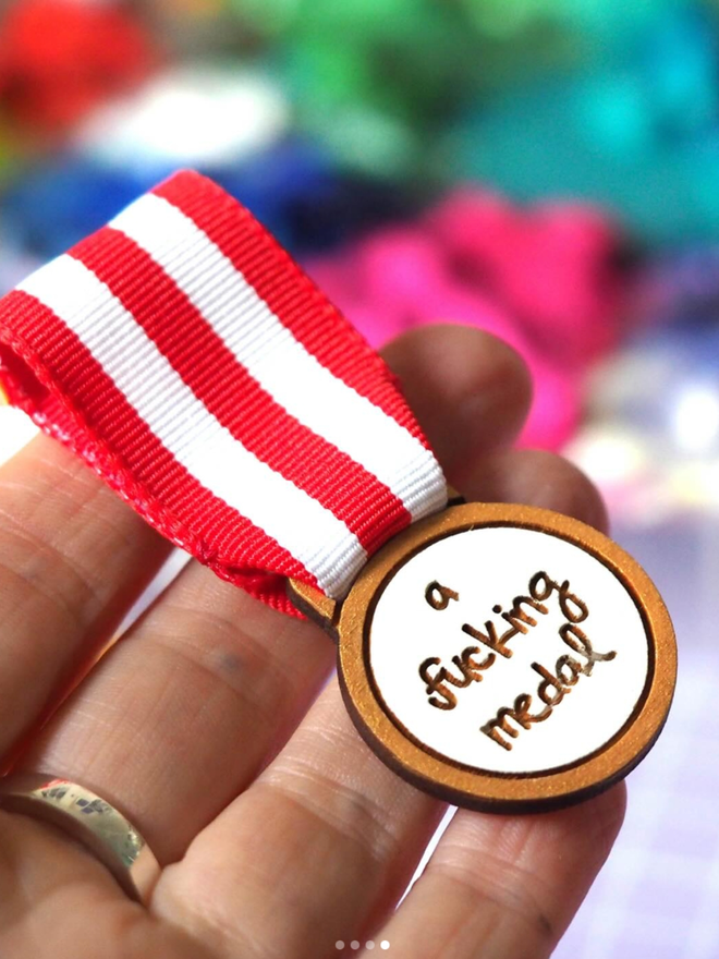 A Wooden Fucking Medal. A wooden medal with red and white ribbon.