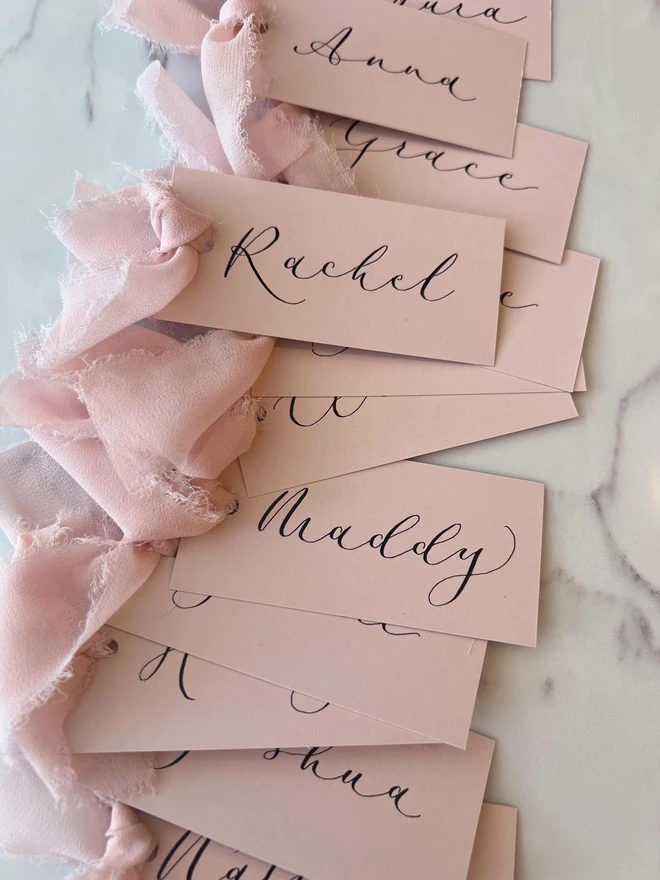 Personalised Calligraphy Wedding Pink Place Cards, pink wedding cards with pink ribbons grouped together. 