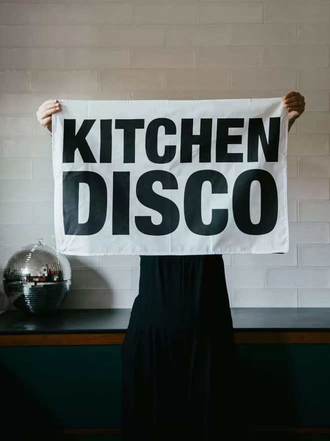 London Drying Kitchen Disco Tea Towel seen held up in a kitchen with a disco ball.