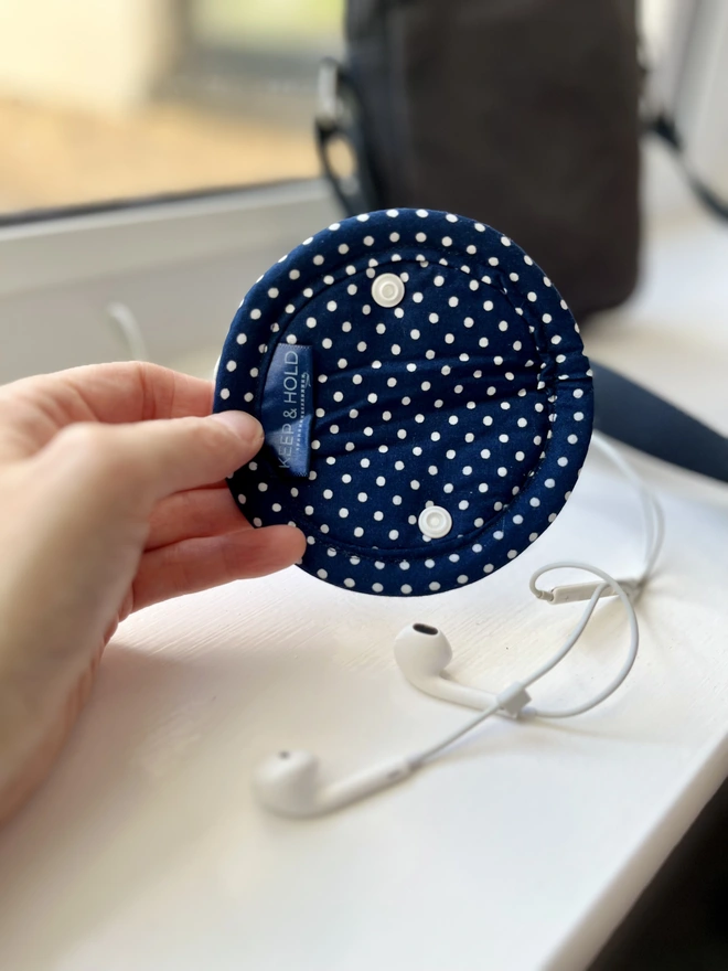 Soft cotton navy polka dot fold-over earphone case with snap close - shown open in a full circle.