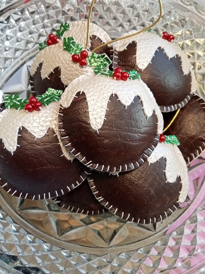 A glass bowl filled with faux leather christmas puddings