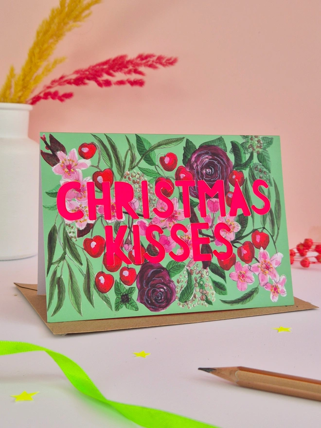 Cherry illustration Card with Christmas kisses in paper cut text with neon pink backing paper 