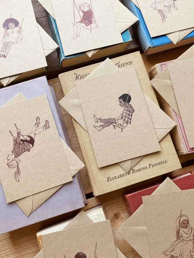 a selection of vintage style drawings of children sat on swings A6 size postcards kraft card with matching kraft envelopes