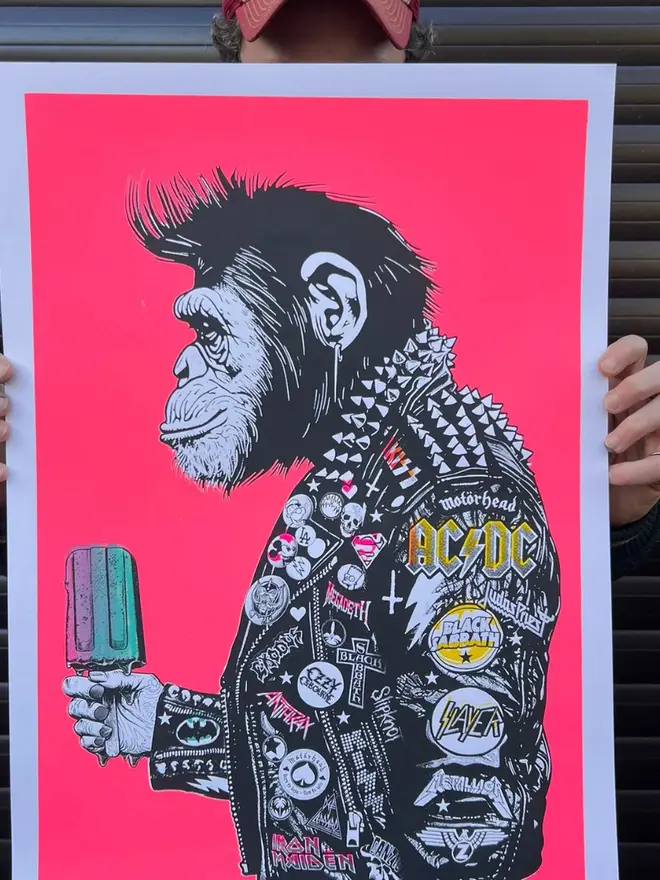 A side profile print of a metal monkey wearing a  punk leather jacket decorated with music band patches, holding an icecream against a neon pink background. 
