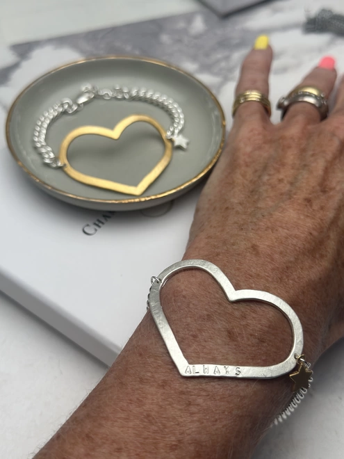 model wears a large personalised silver open star on a chunky curb bracelet, with a small gold star charm.  Gold version of the bracelet in the background