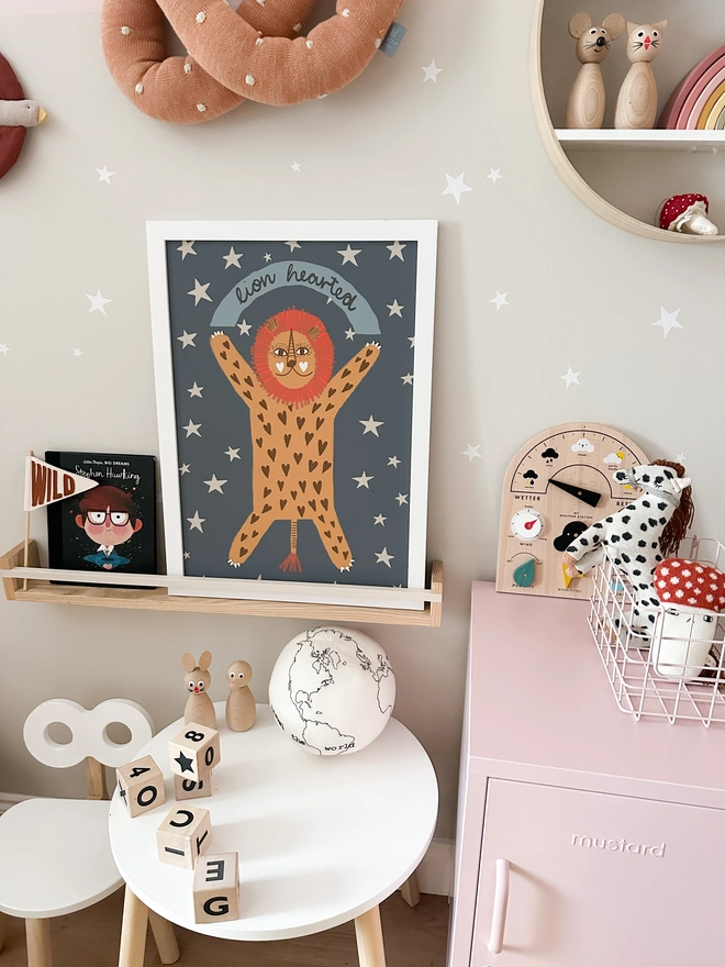 A quirky and fun lion illustration print on a muted blue background with stars around him. 