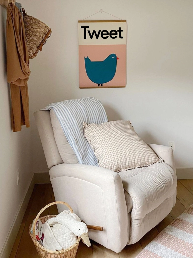 Wall print illustrated blue bird on pink background on a wall behind an armchair