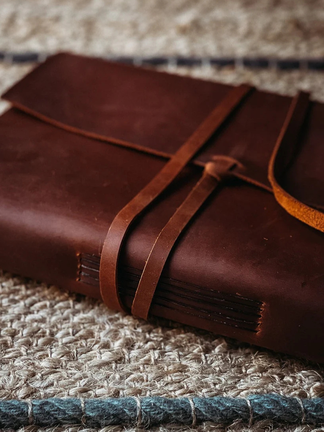  leather refillable ring binder. a dark brown leather ring binder photographed on a rug.