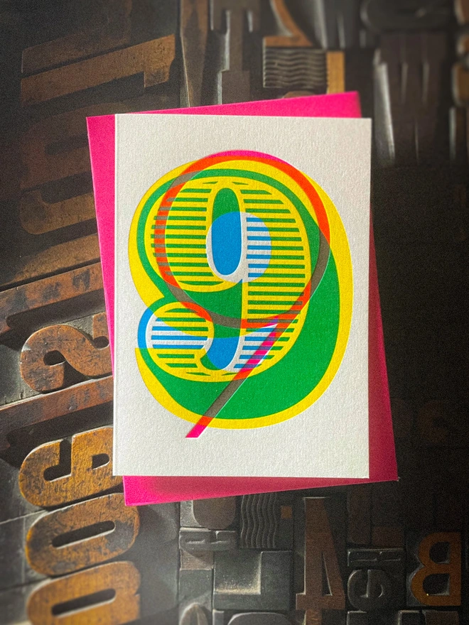 Handmade letterpress 9th birthday card featuring bold overlapping numerals printed in vibrant fluorescent cyan, magenta and yellow inks. Each card is individually hand printed using traditional letterpress techniques on luxury paper stock, creating a beautifully tactile finish with a deep impression and rich layered colours inspired by the CMYK printing process. Printed on a traditional letterpress from 1915. A wonderful artisan printed birthday card.