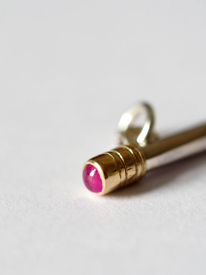 Close up image of a Ruby dinky pencil charm on a table