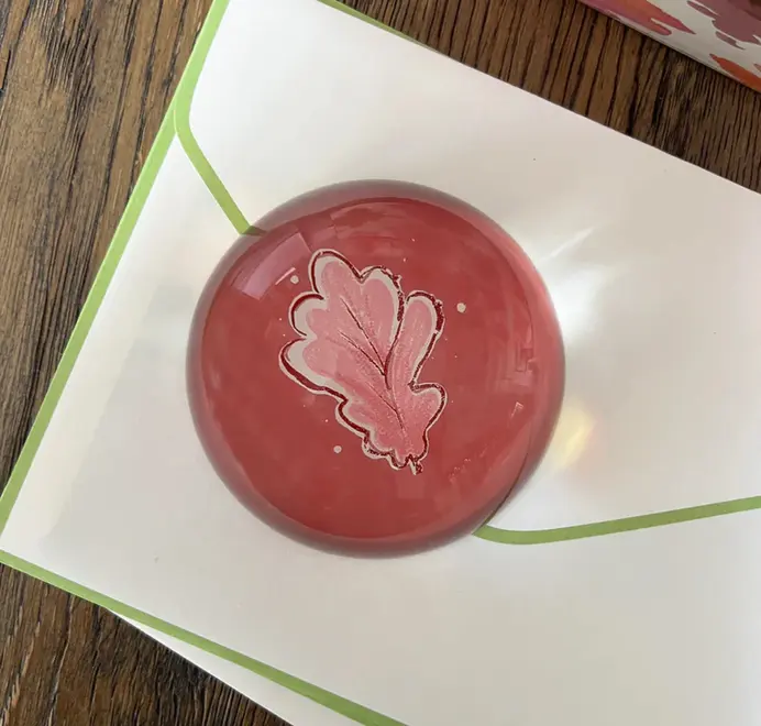 Round pink oak leafpaper weights on a wooden table. 