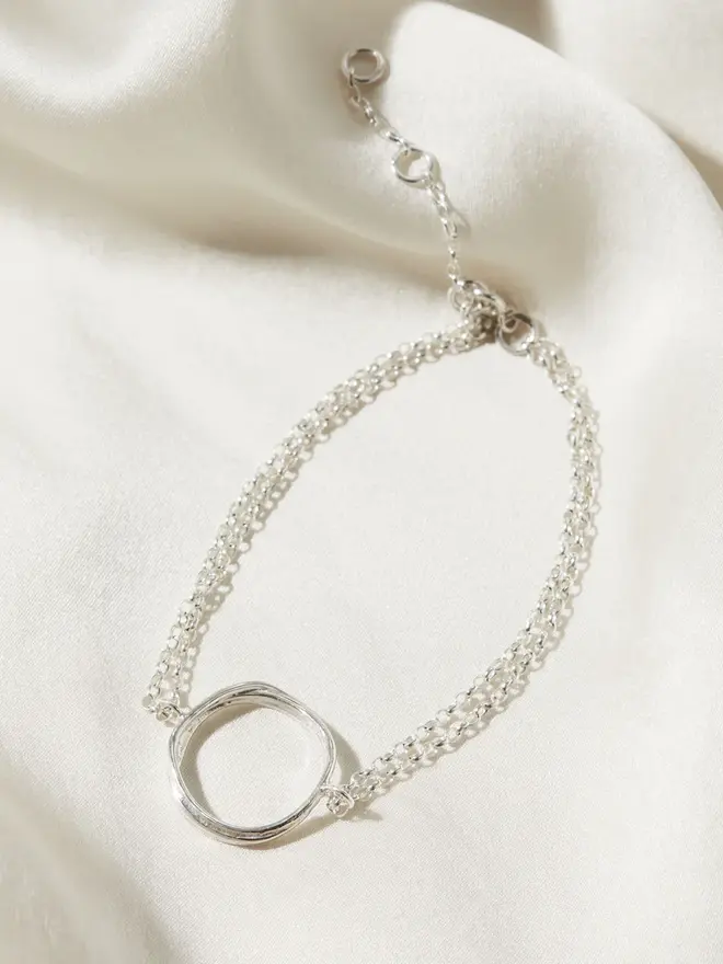 Silver Organic Circle Bracelet draped on silk material
