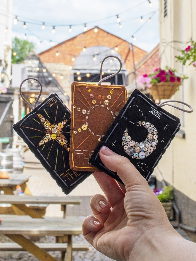 A handcrafted felt ornament with sequins and embroidery depicting "The Moon" tarot card. Also accompanied by “The Sun and The Star”