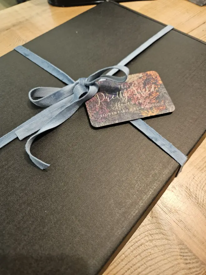 Letterbox Flowers, a colourful collection of flowers sitting in their letterbox packaging on a wooden surface. 