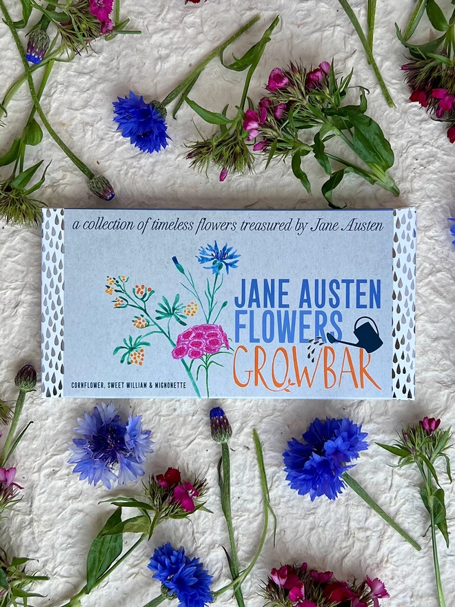 The Jane Austen Growbar laying on a bed of blue cornflowers and pink sweet William flowers.