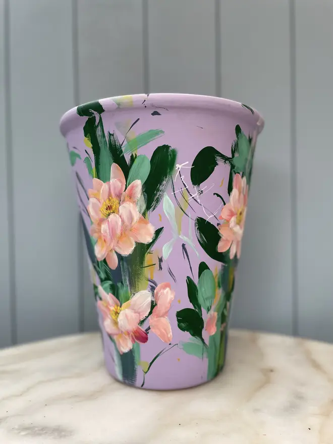 Unique hand-painted terracotta pot featuring apricot geum flowers on a lilic background