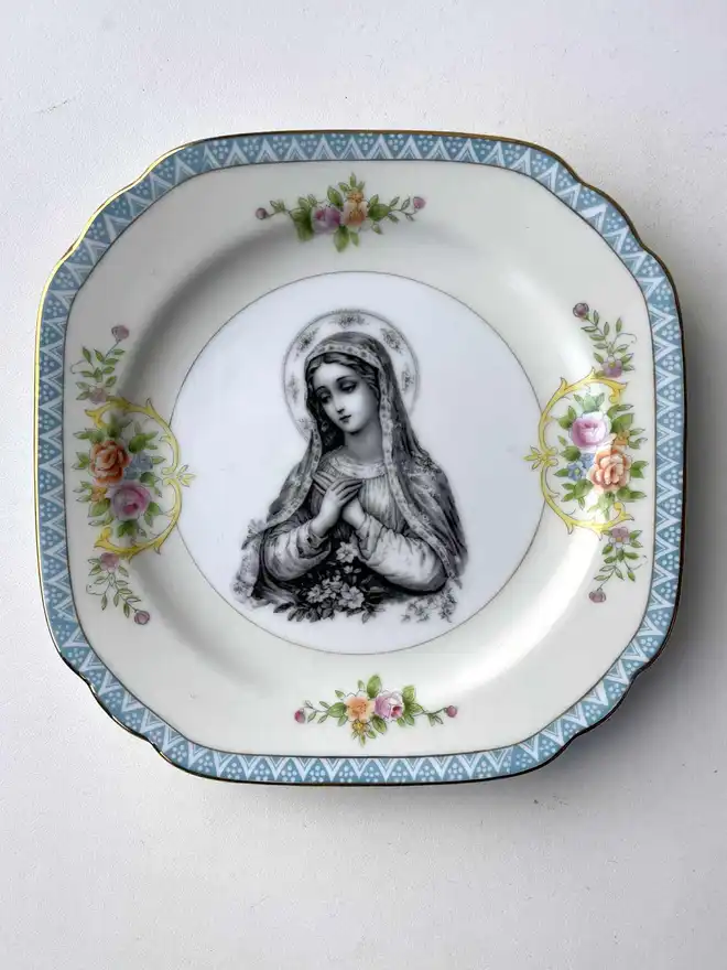 a vintage plate with a really ornate border has the victorian black and white illustration of the virgin mary in the centre