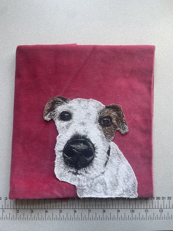 an embroidered pet portrait by Rocketfullofpie sitting on a pile of pink velvet background fabric